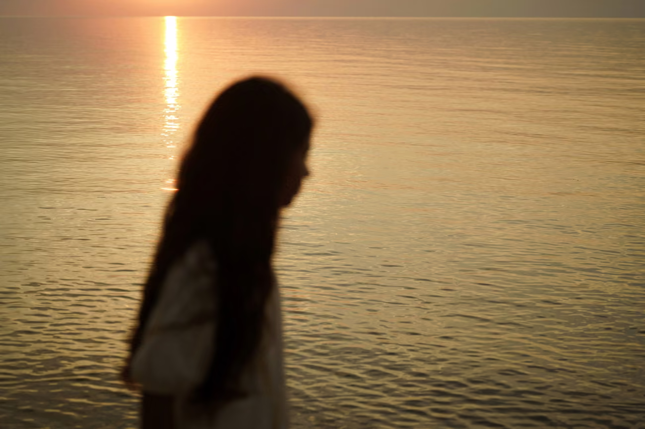 Une femme songeuse au bord de l'eau, au crépuscule